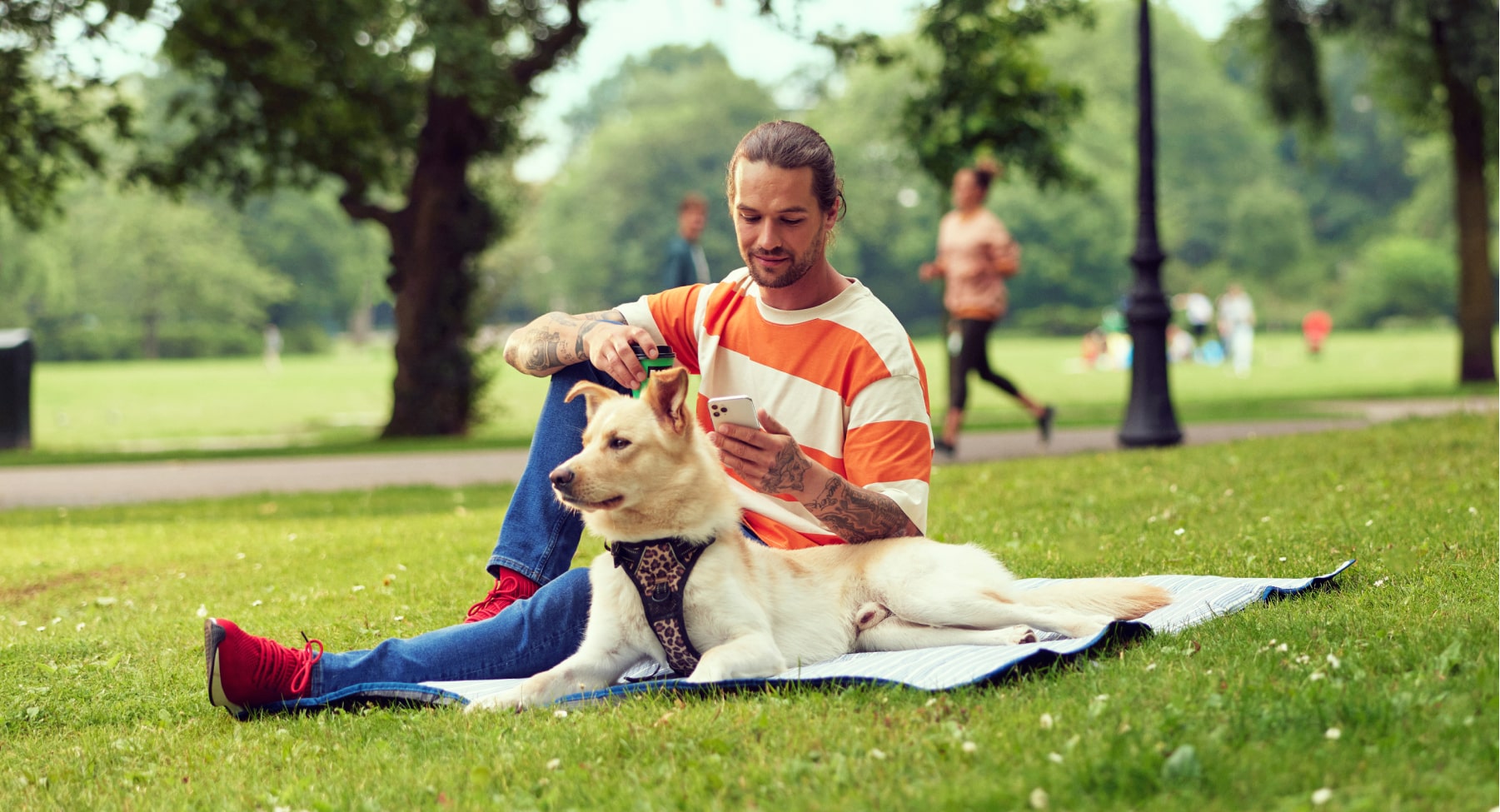Man using his phone in park with his dog
