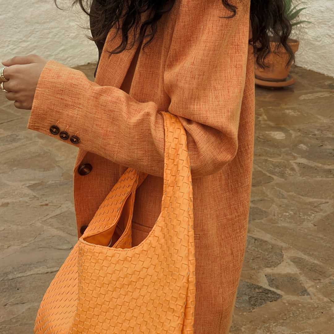 postać w pomarańczowym płaszczu z pomarańczową torbą