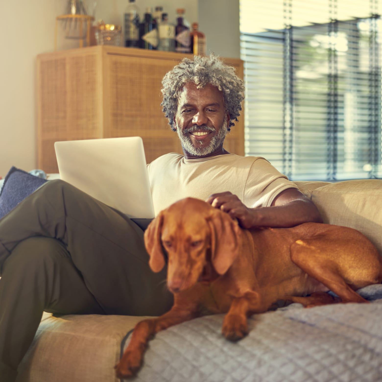 Person, die auf der Couch neben einem Hund eine Online-Zahlung tätigt